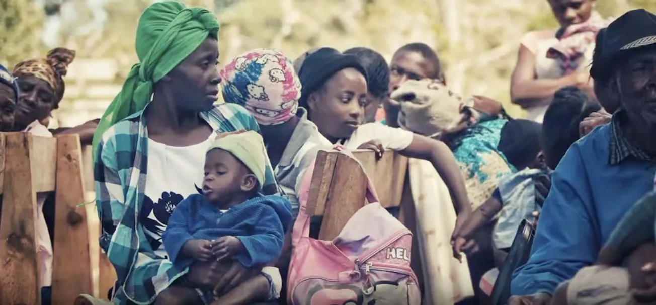 A mother holding her baby among a crowd of families waiting together in Haiti